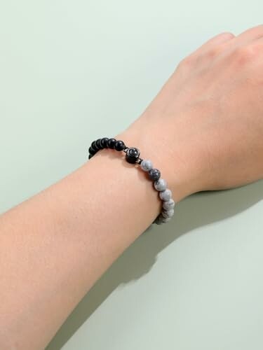 Bracelet de perles noires et blanches sur un poignet.