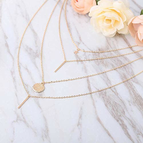 Collier en or à plusieurs couches sur fond de marbre avec des fleurs.