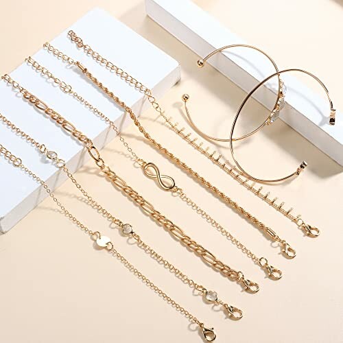 Ensemble de bracelets en chaîne dorée sur fond beige.