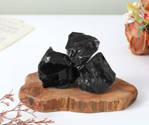 Trois pierres noires polies sur une base en bois.