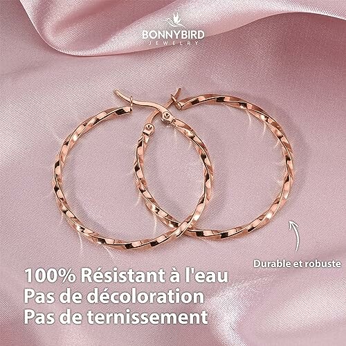 Boucles d'oreilles en or rose sur tissu rose.